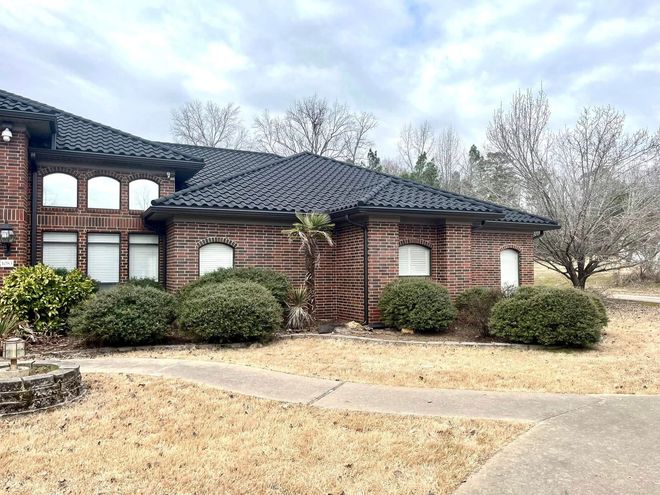A large brick house with a black roof is for sale.