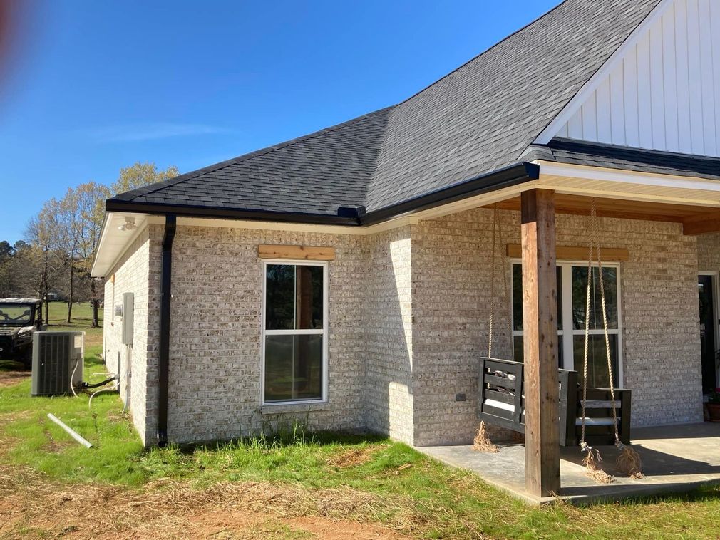 The back of a brick house with a porch and a swing.