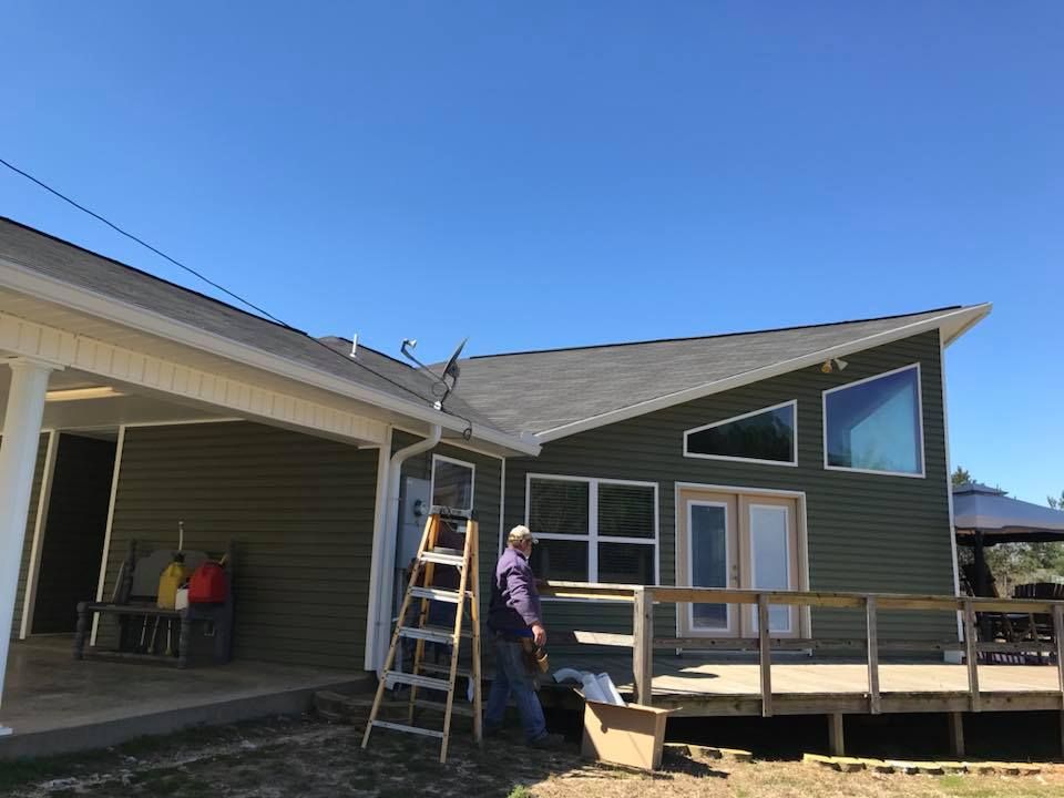 A man is standing on a ladder in front of a house.
