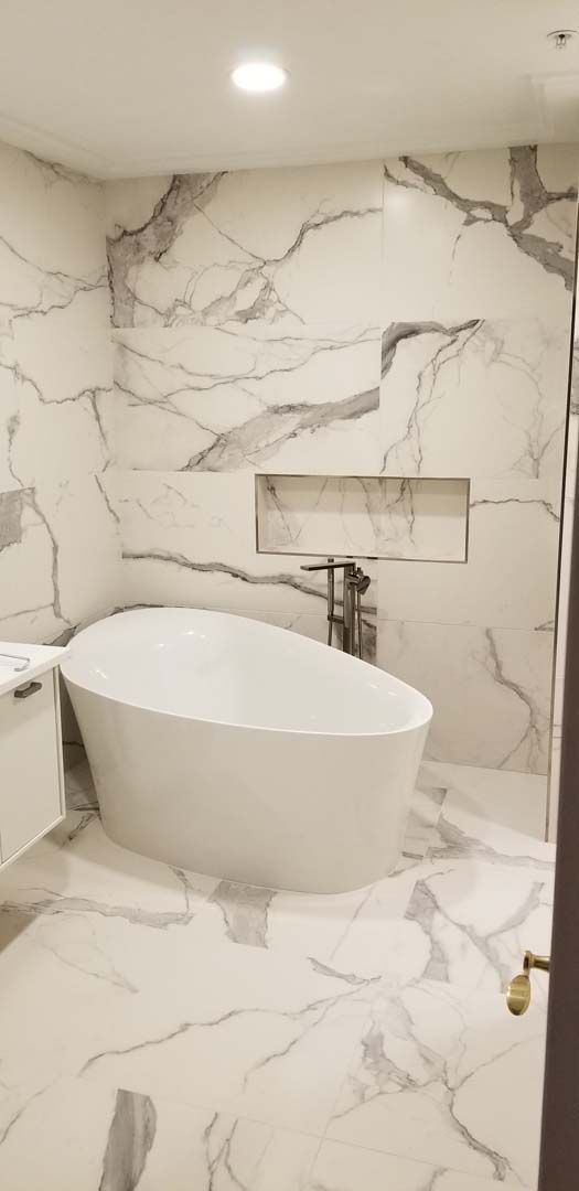 A bathroom with marble tiles and a bathtub.
