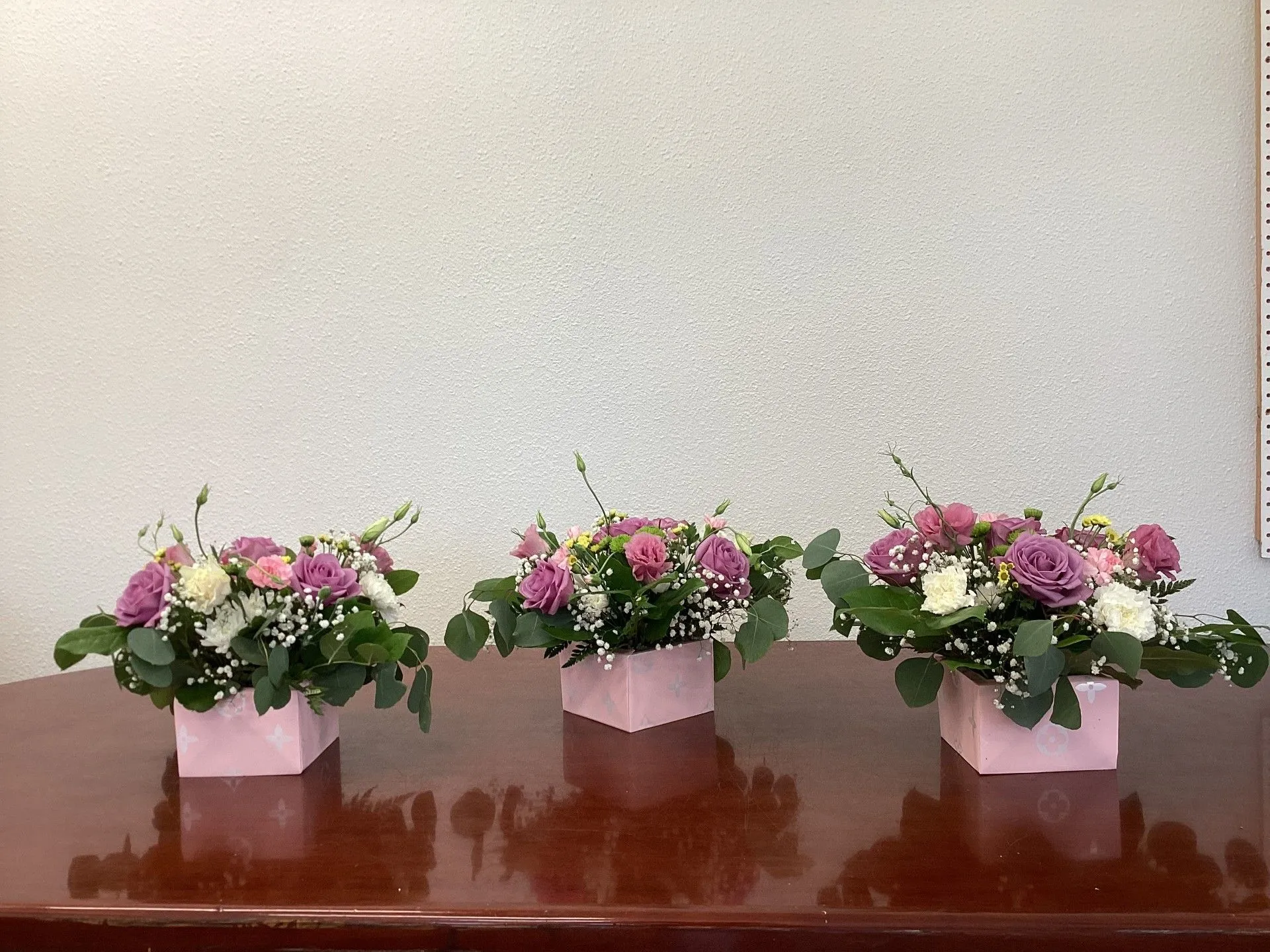 Three pink vases filled with flowers
