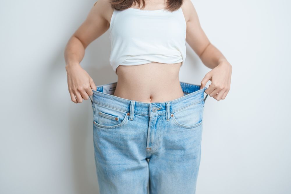 A woman is wearing a pair of very large jeans.