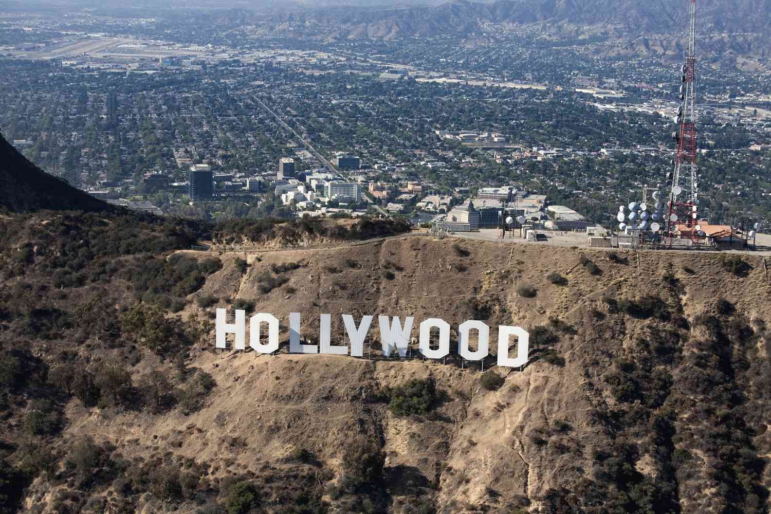 Hollywood sign on a hillside with city and mountains in the background.