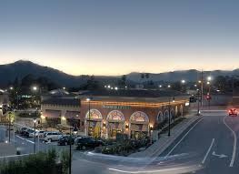 Dusk scene with a restaurant and street corner. Mountains in the background, cars and lights visible.