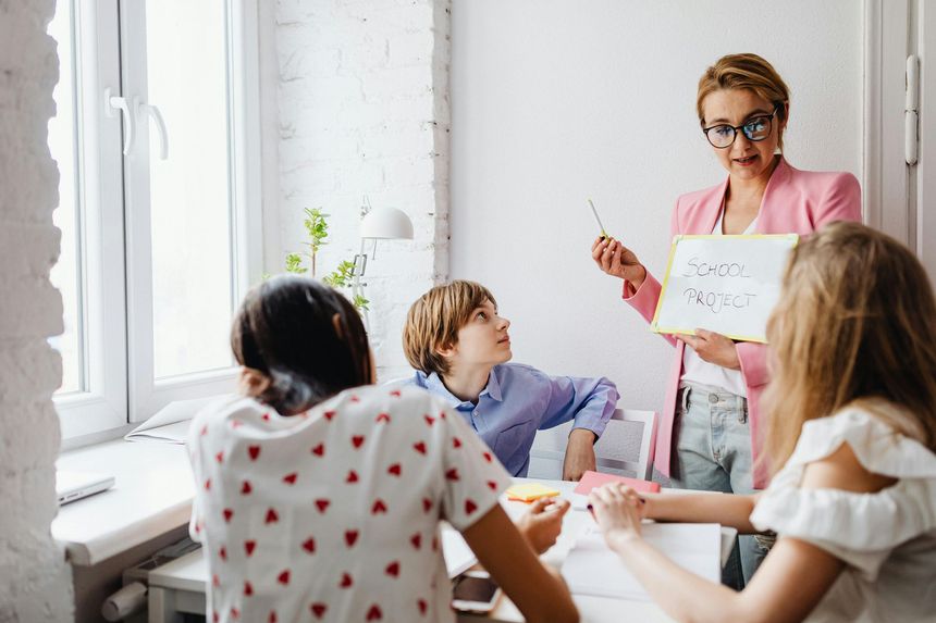 Teacher presenting to a group in a bright classroom with a whiteboard and seated students
