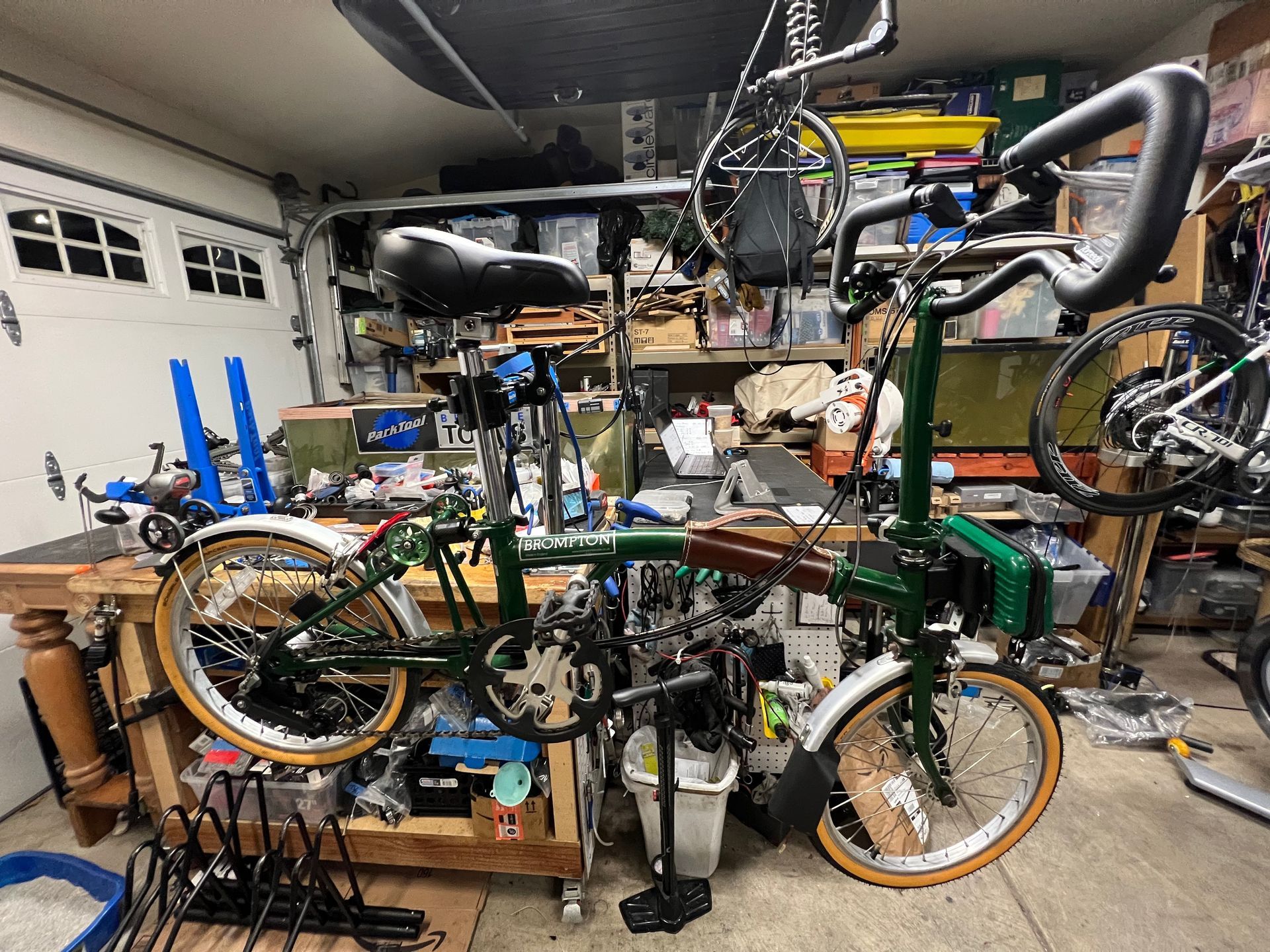 Green folding bicycle in a cluttered garage, workbench nearby.