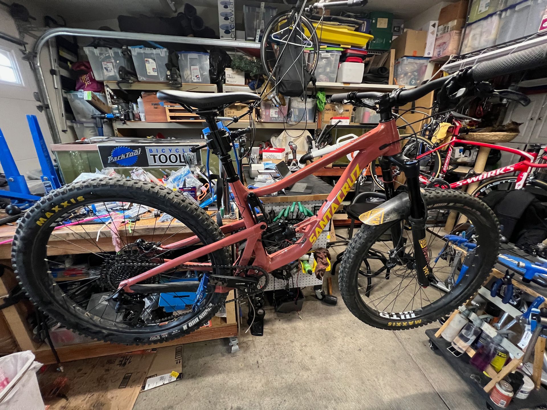 Red mountain bike in a cluttered garage, angled view.