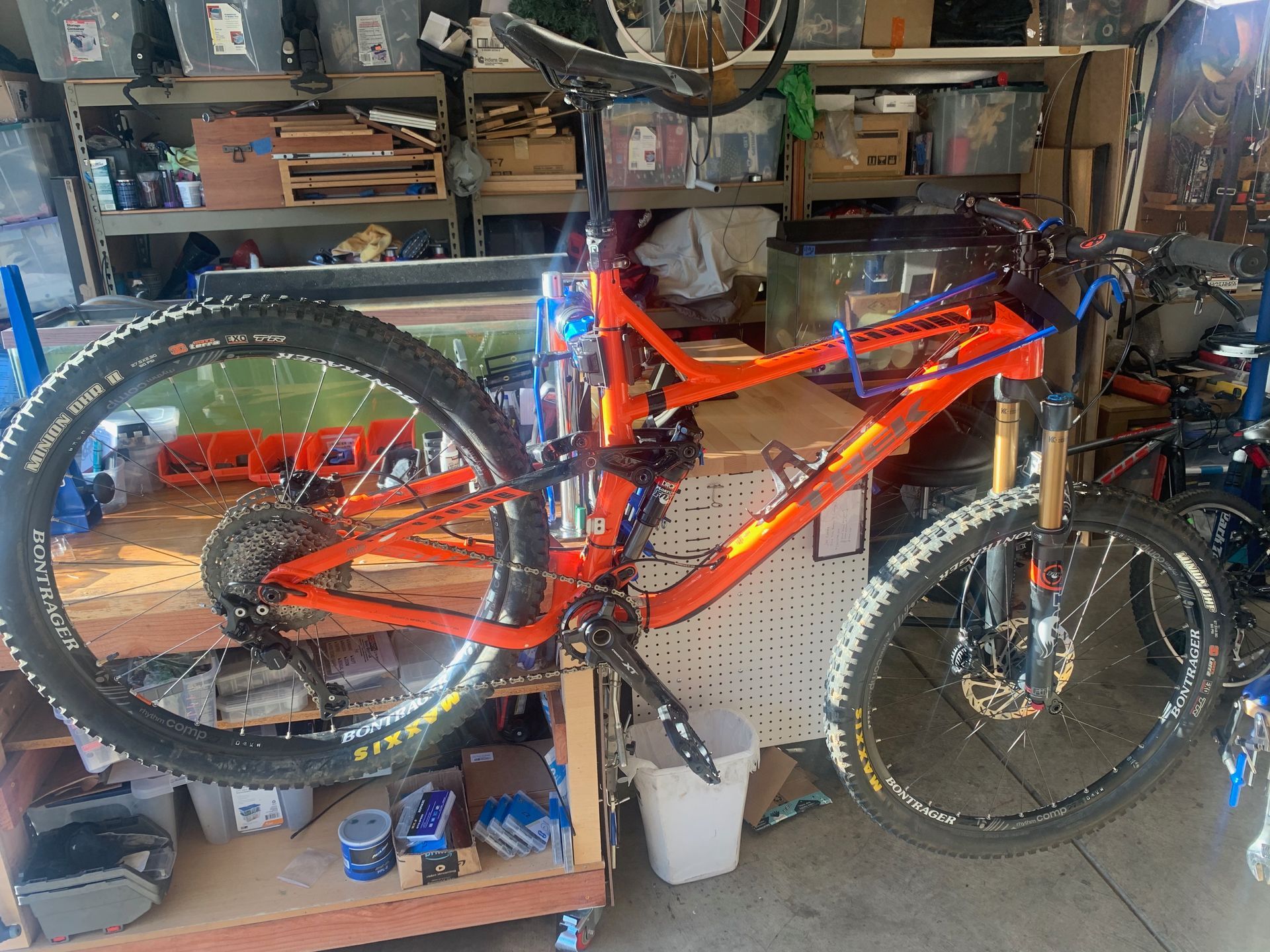 Orange mountain bike in a garage with tools and equipment.