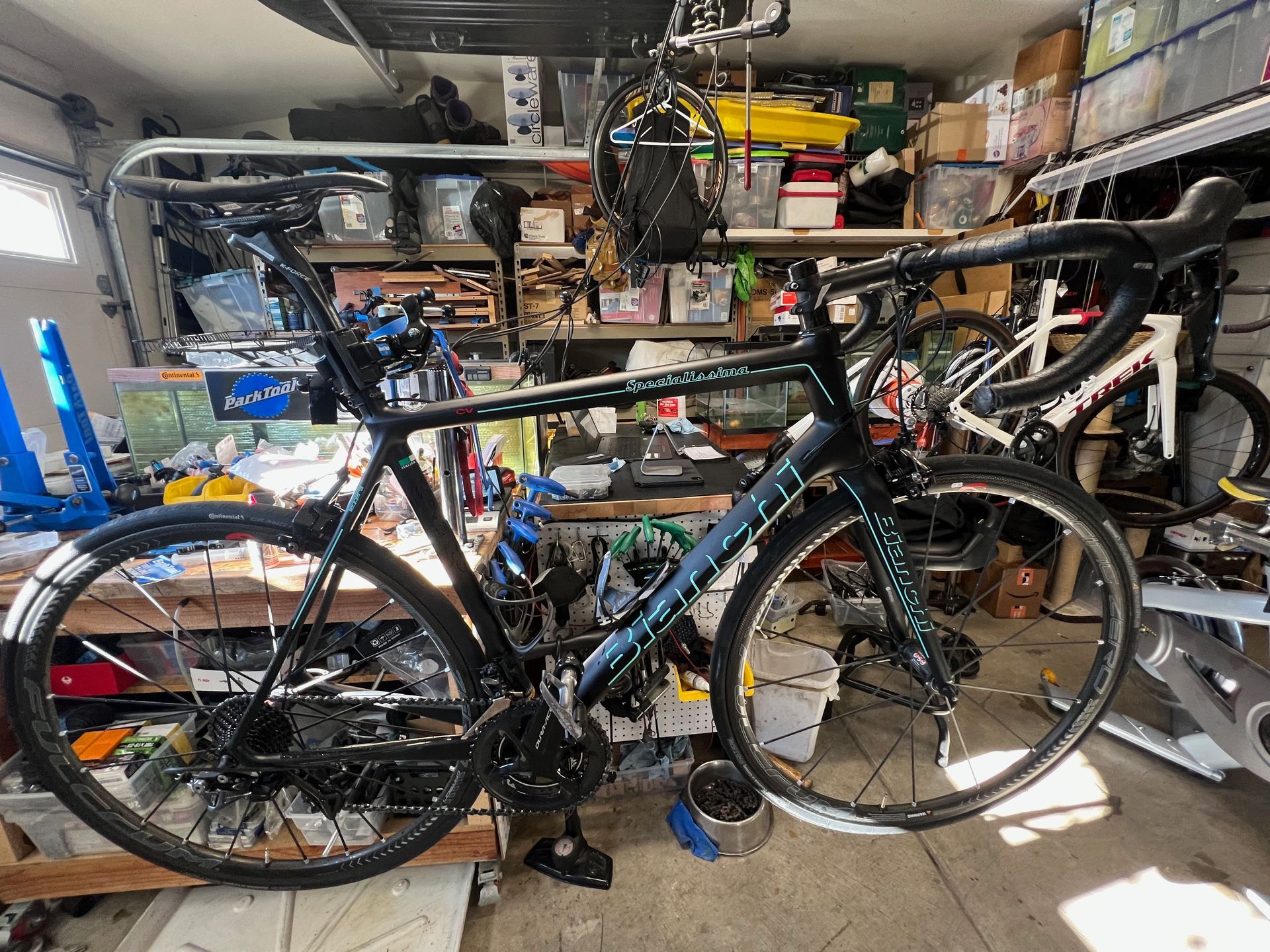 Black road bicycle with teal accents in a cluttered garage setting.