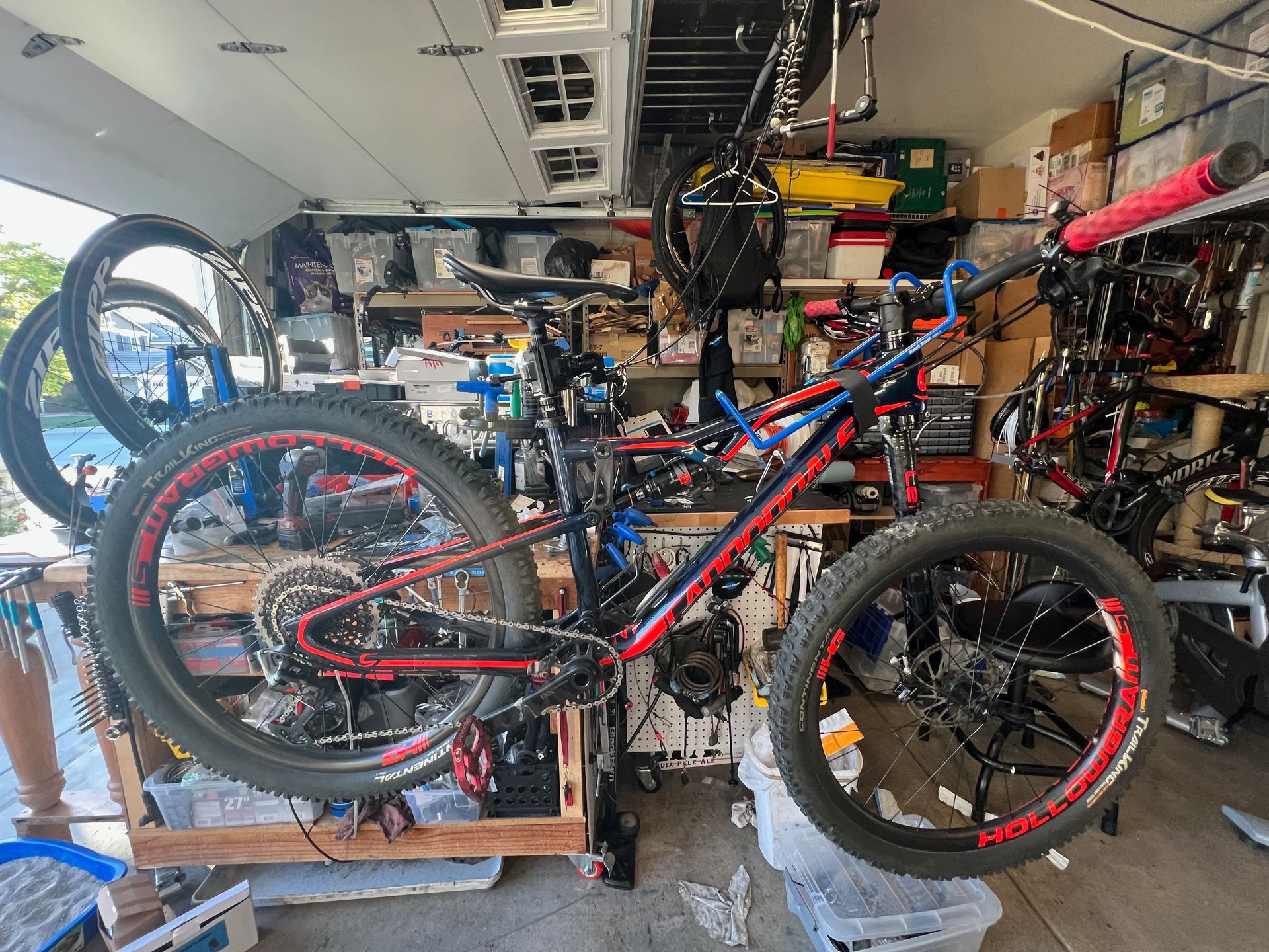Fat tire mountain bike in a garage workshop, black frame with red accents, various tools and parts visible.