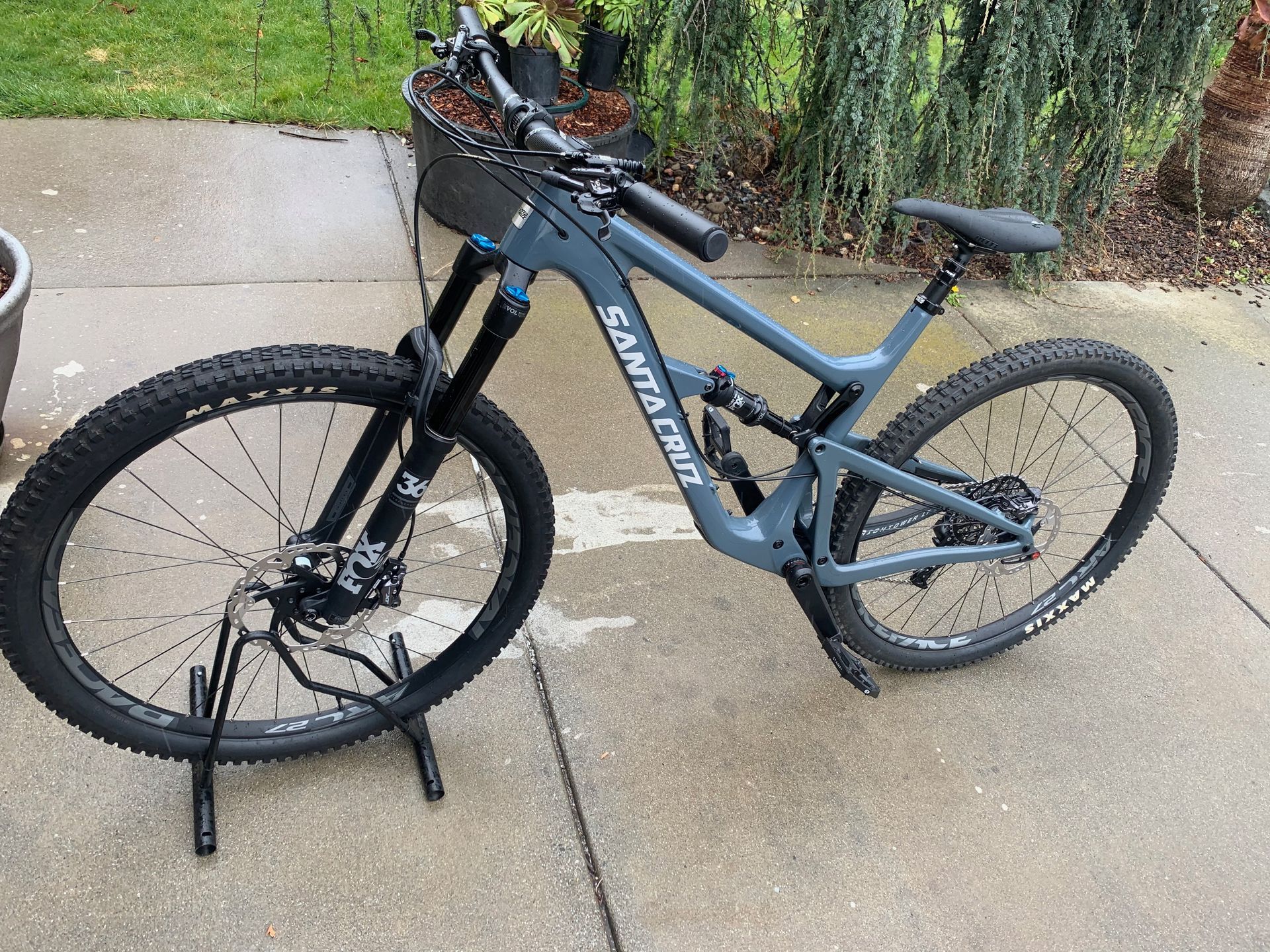 Gray Santa Cruz mountain bike on a stand outside on a concrete surface.