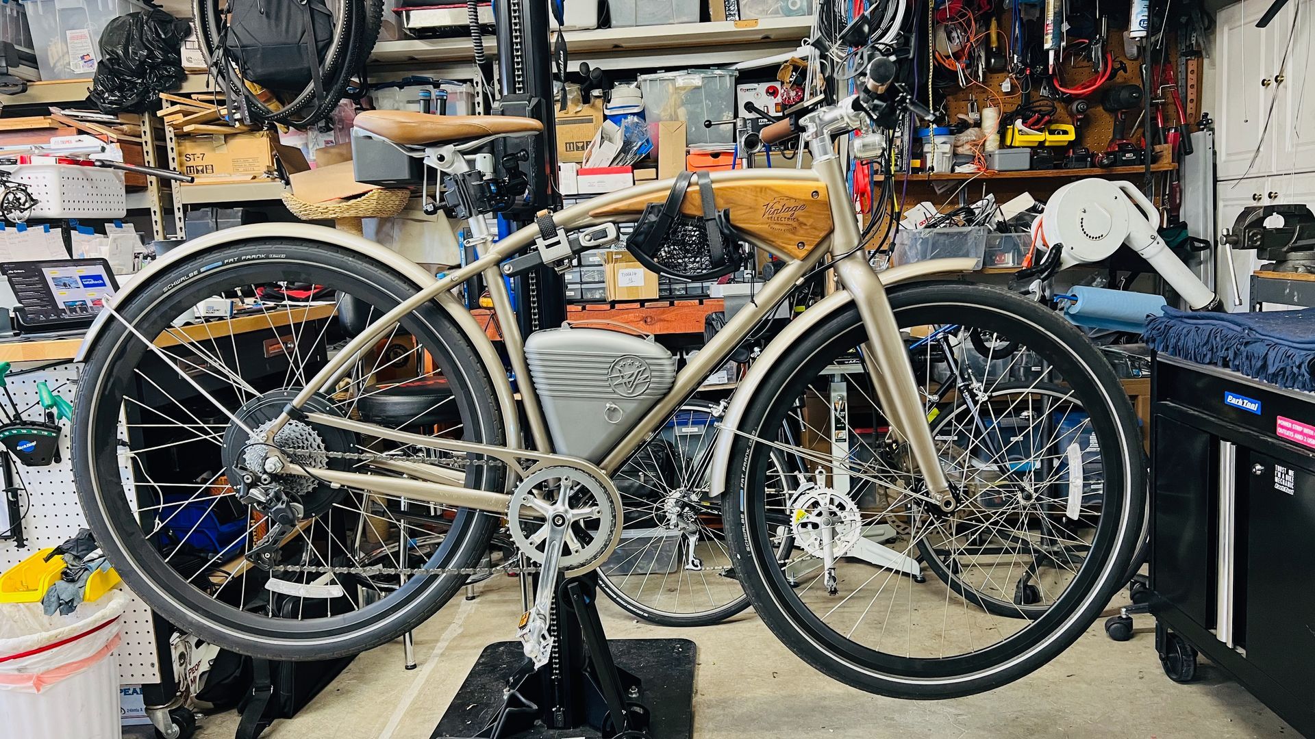 Custom-built electric bicycle with a wooden frame and battery, in a workshop setting.