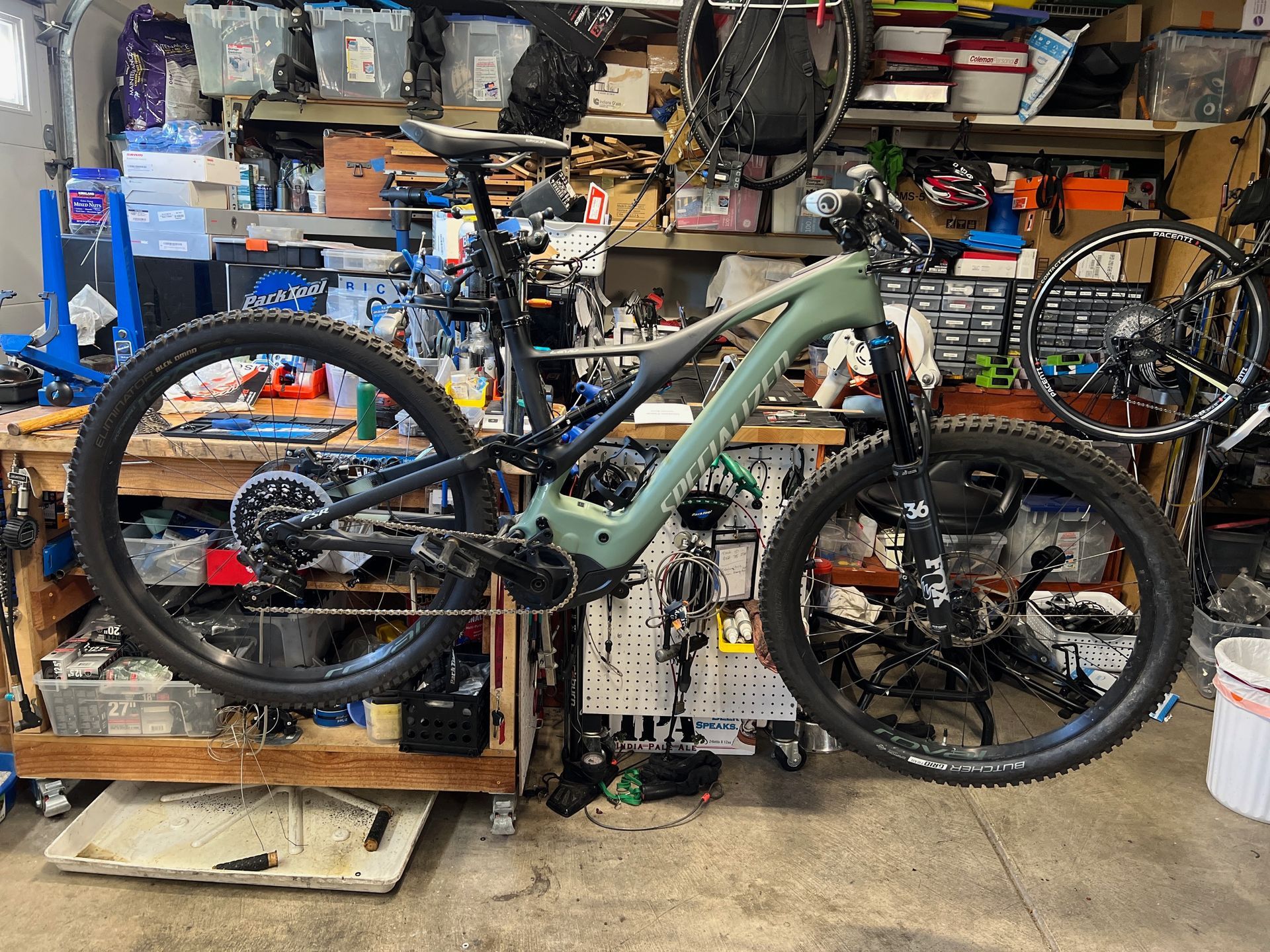 Green mountain bike in a cluttered garage, likely for maintenance.
