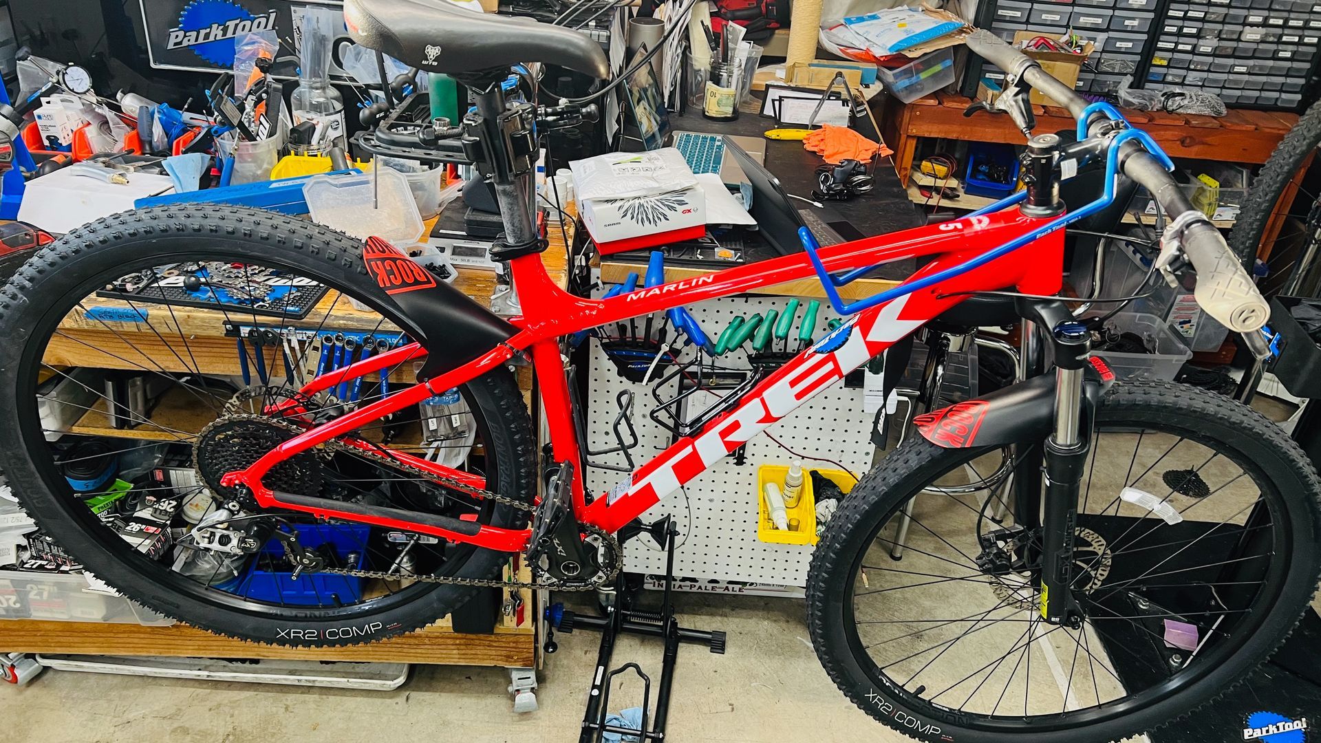 Red and white Trek mountain bike in a cluttered bike shop.