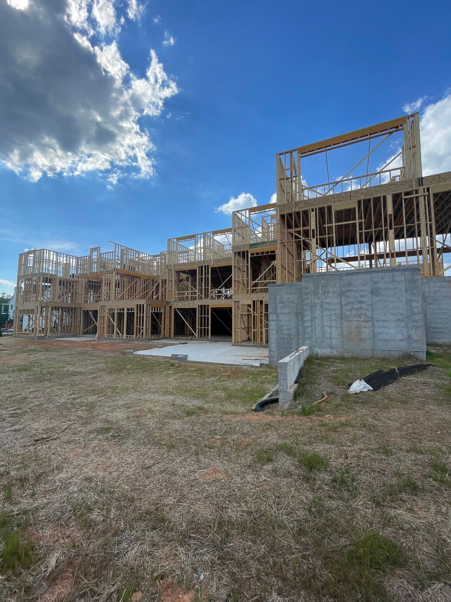 A large house is being built in a field with a blue sky in the background.