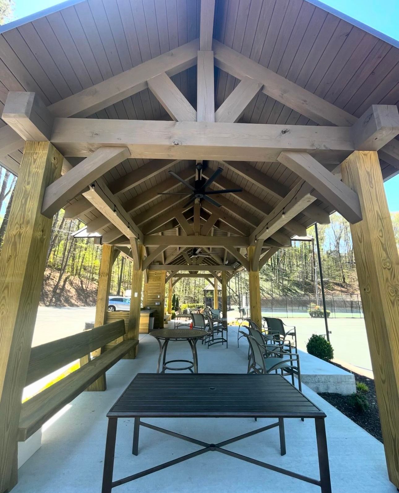 A wooden gazebo with tables and chairs underneath it