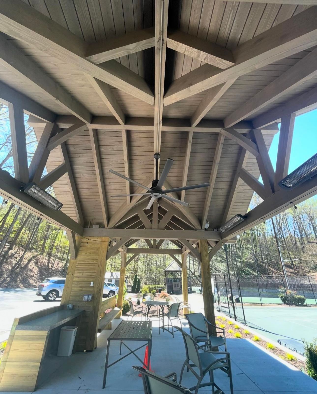 A gazebo with tables and chairs and a ceiling fan