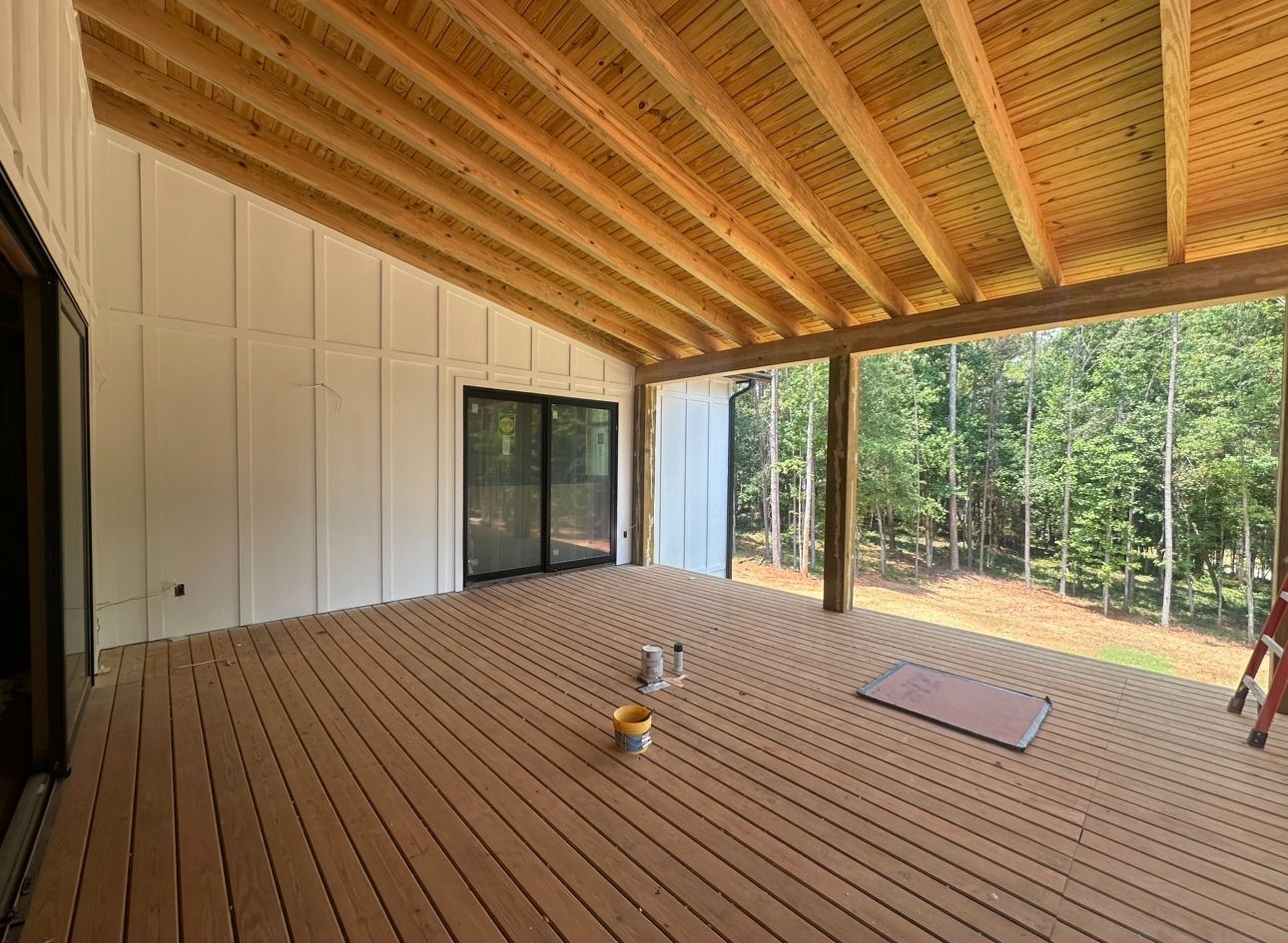 A large deck with a wooden roof and sliding glass doors.