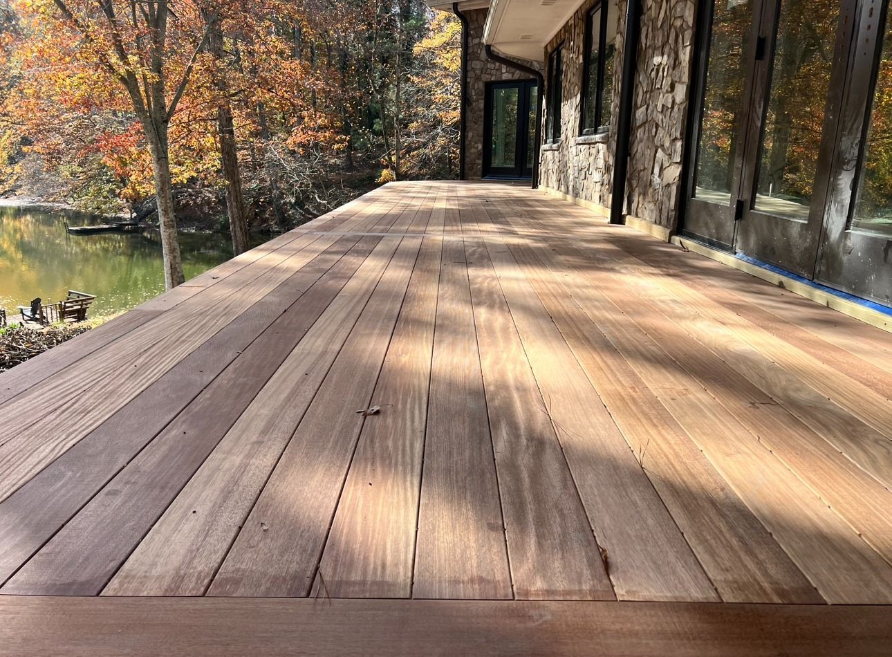 A wooden deck with a view of a lake and trees.