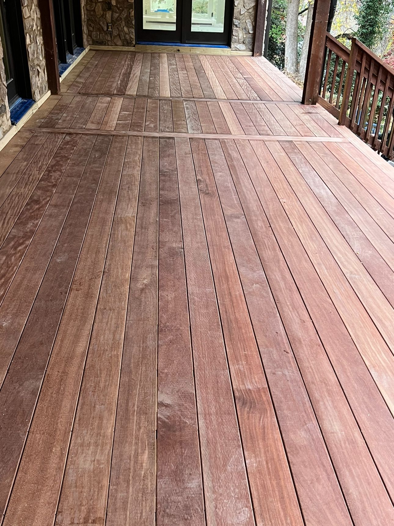 A large wooden deck with a railing and sliding glass doors.
