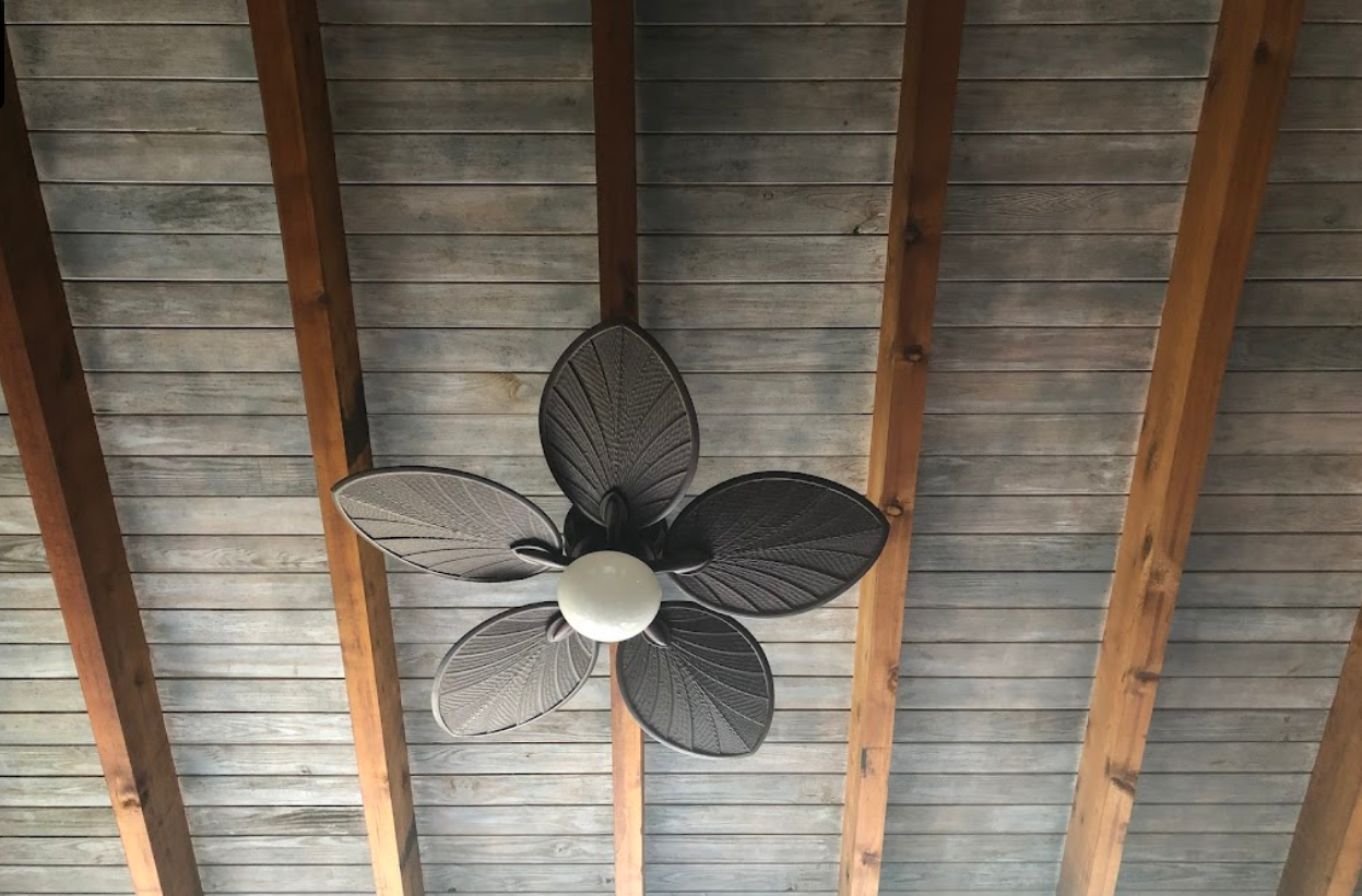 A ceiling fan is hanging from the ceiling of a wooden structure.