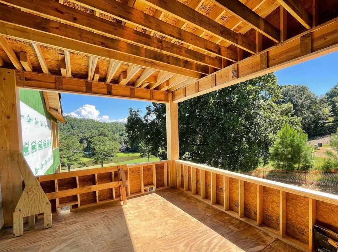 A wooden porch with a view of a lush green forest.