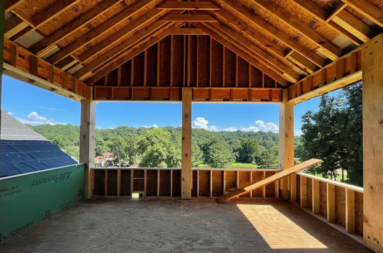 An empty room with a wooden roof and a view of trees