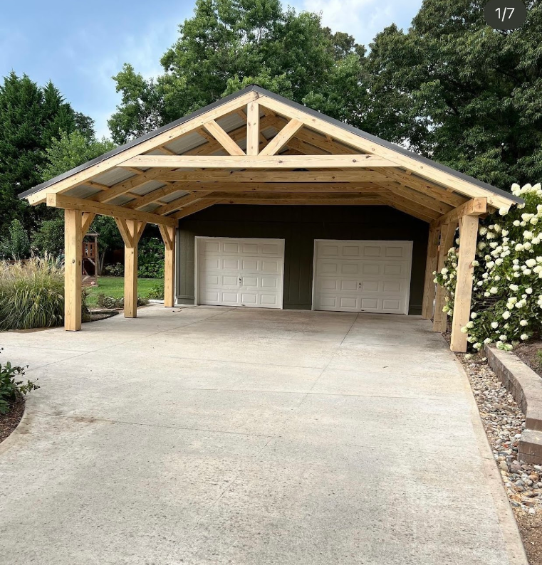A garage with a wooden roof and a concrete driveway
