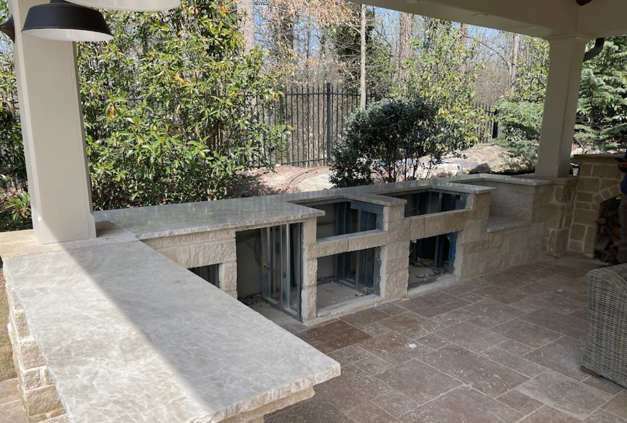 A large outdoor kitchen is being built in a backyard.