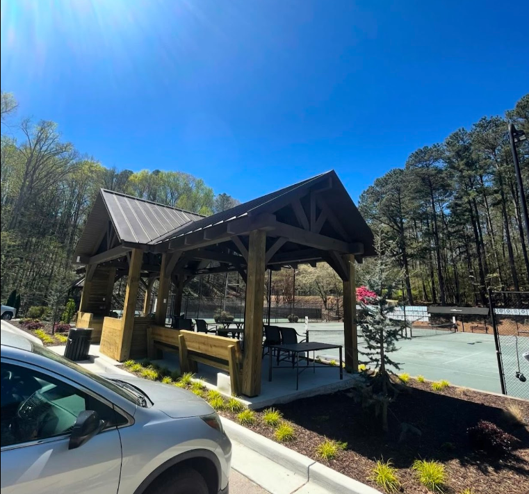 A car is parked in front of a wooden gazebo