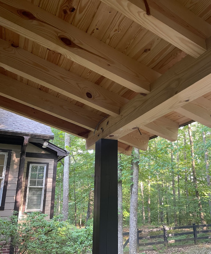 A wooden porch with a fence in the background and a house in the background