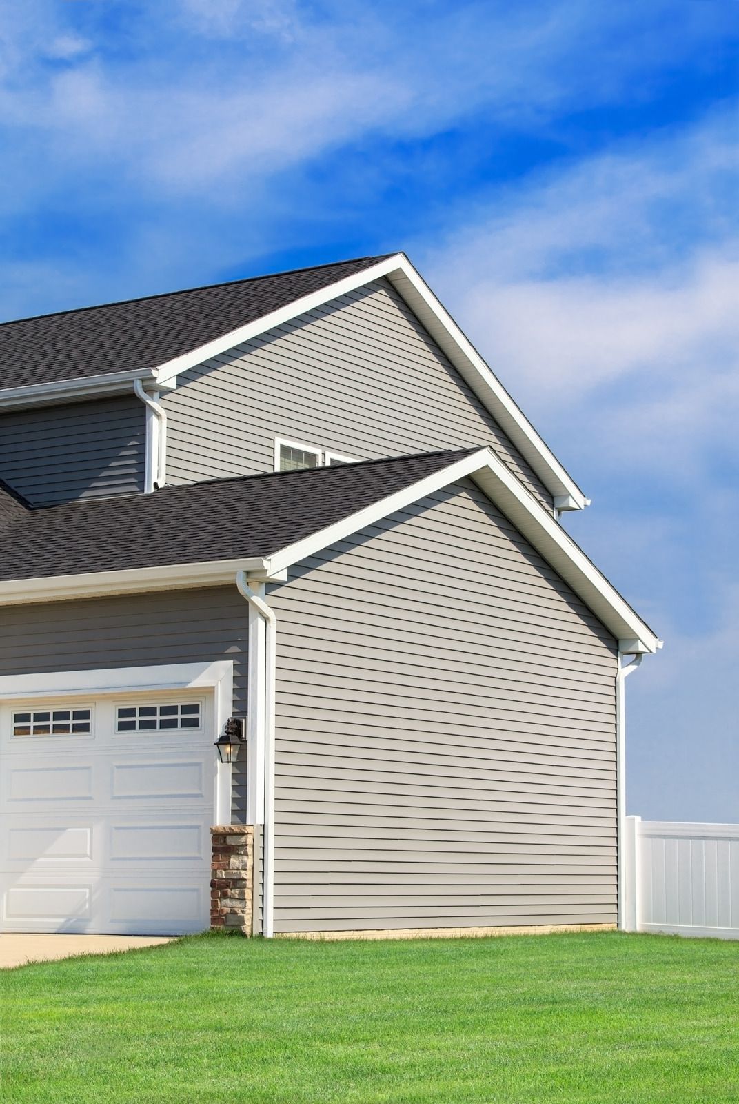 A house with a garage and a fence in front of it