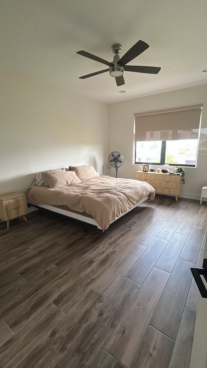 A bedroom with a bed and a ceiling fan.