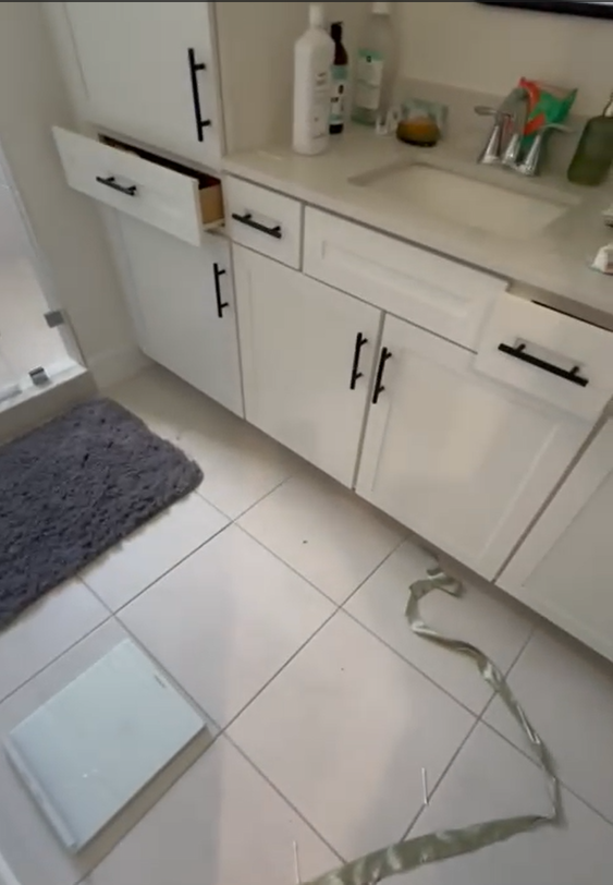 A bathroom with white cabinets and a scale on the floor