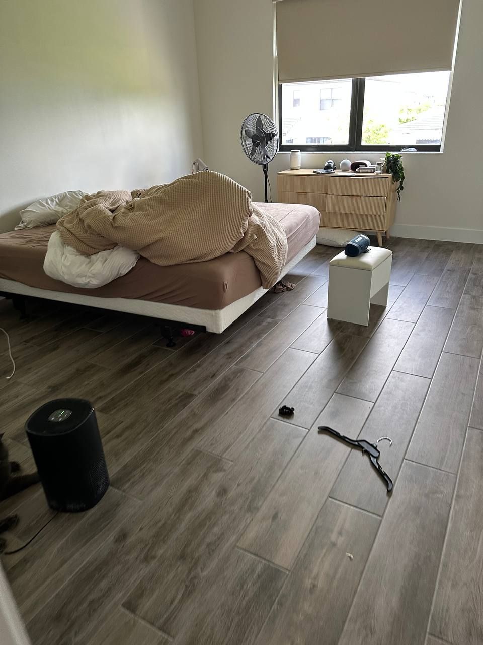 A bedroom with a bed , dresser , and fan.
