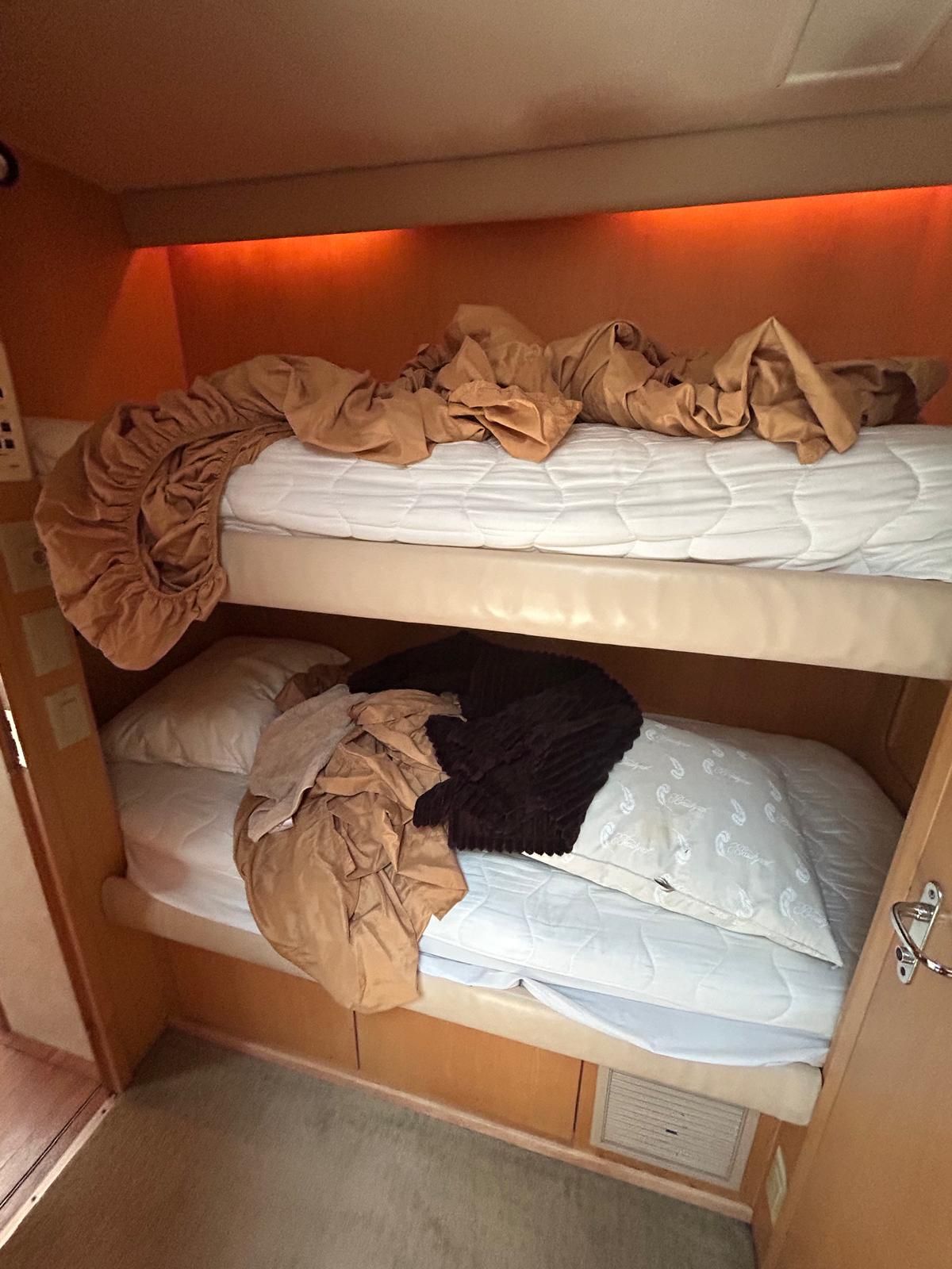 A bunk bed with a blanket on top of it in a room.