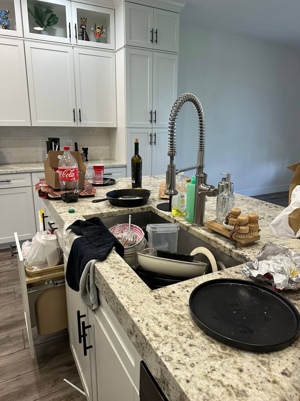 A kitchen with a sink and a bottle of coca cola on the counter.