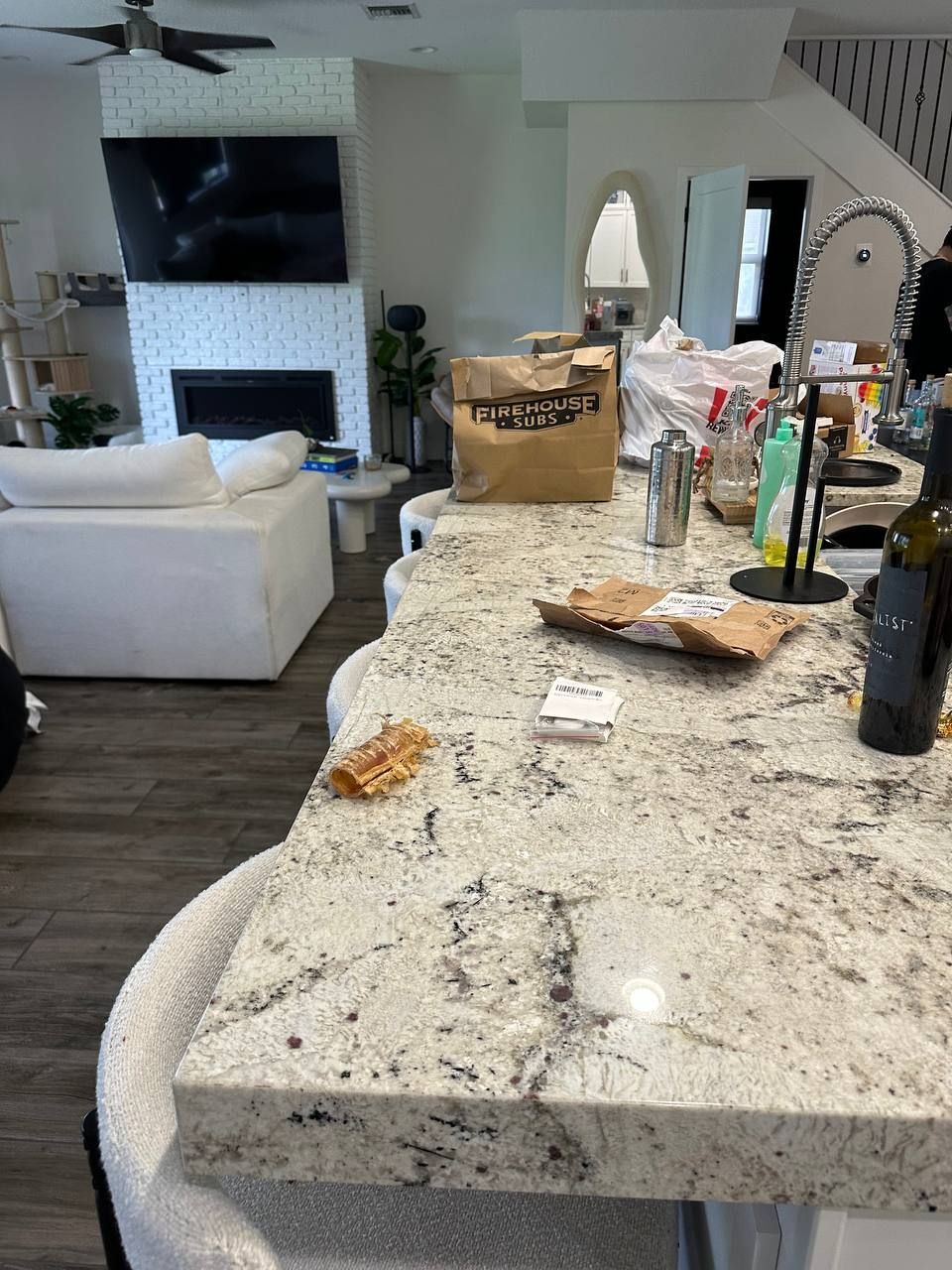 A kitchen counter with a bag on it and a bottle of wine on it.