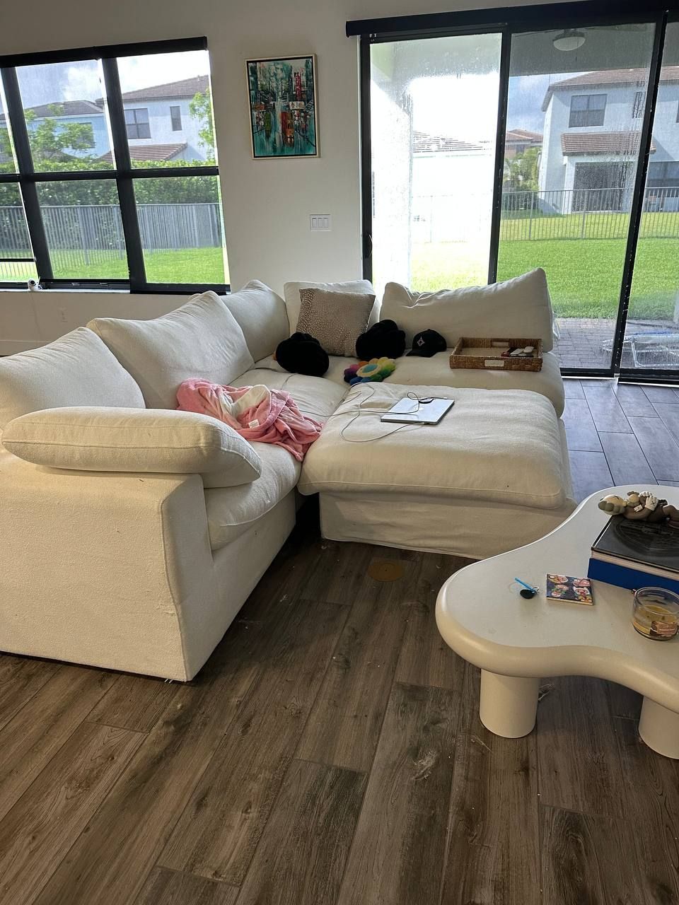 A living room with a white sectional couch and a white coffee table.