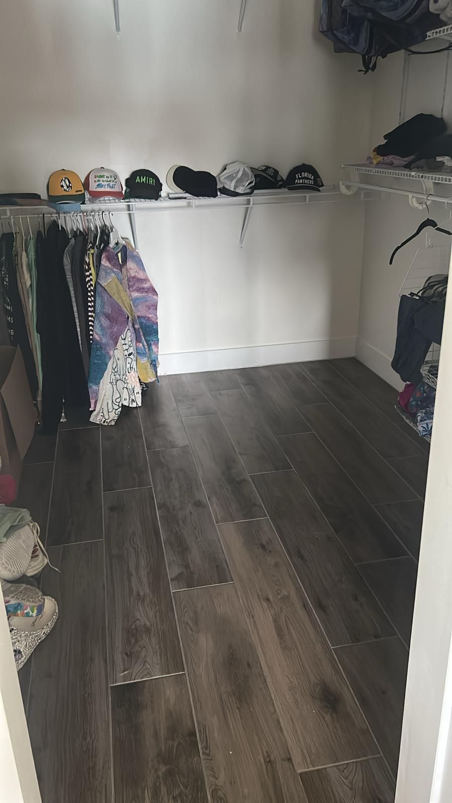 A walk in closet filled with clothes and hats.