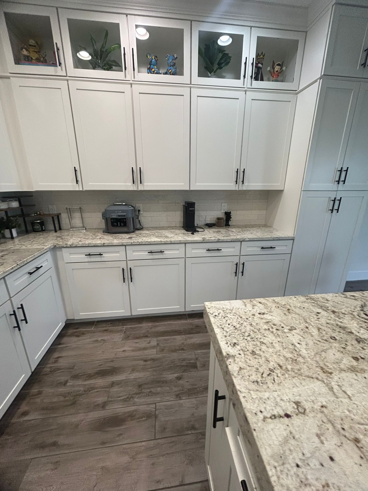 A kitchen with white cabinets and granite counter tops.