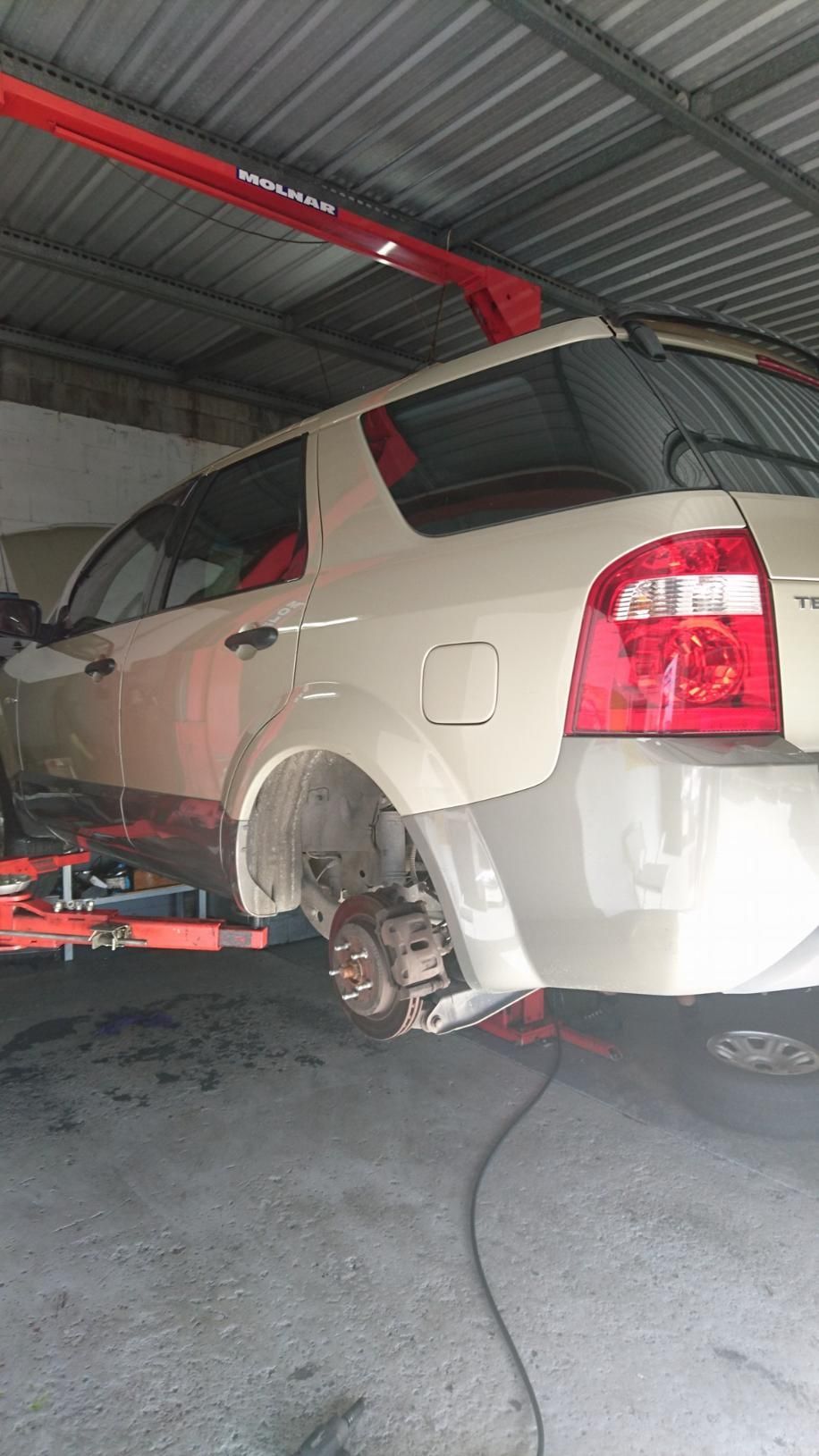 A White Car is Sitting on a Lift in a Garage — Step Up Automotive in Southport, QLD