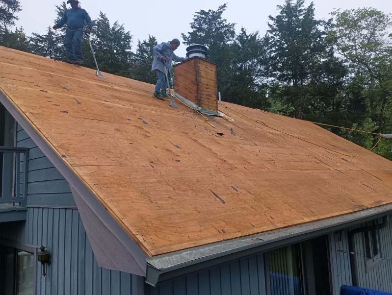 Two men are working on the roof of a house