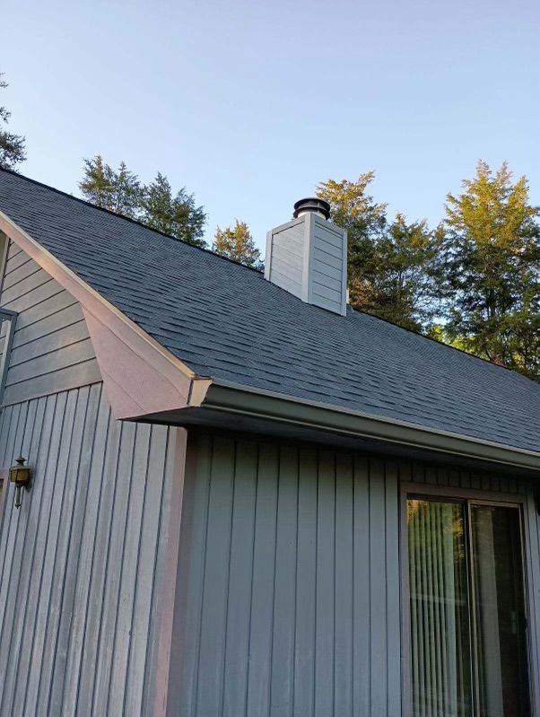 A house with a chimney on the roof and trees in the background.