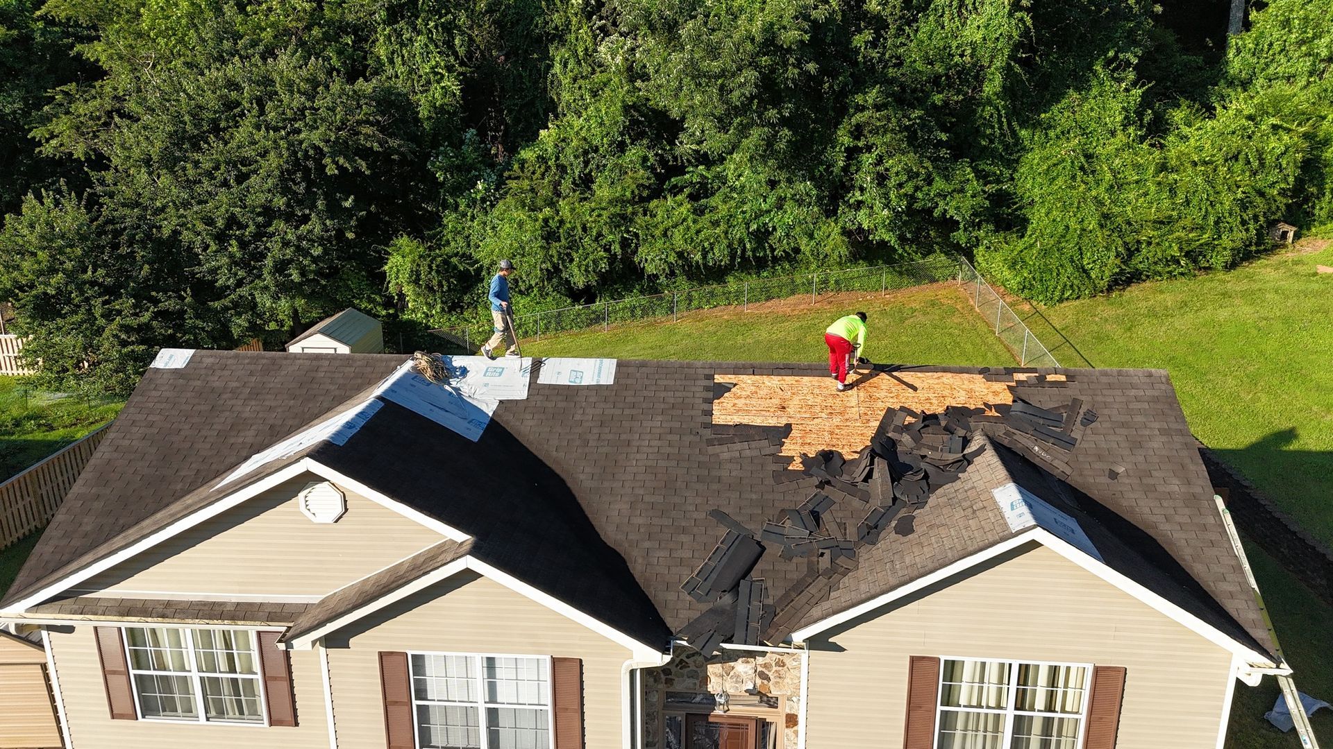 An aerial view of a house with a roof being repaired.