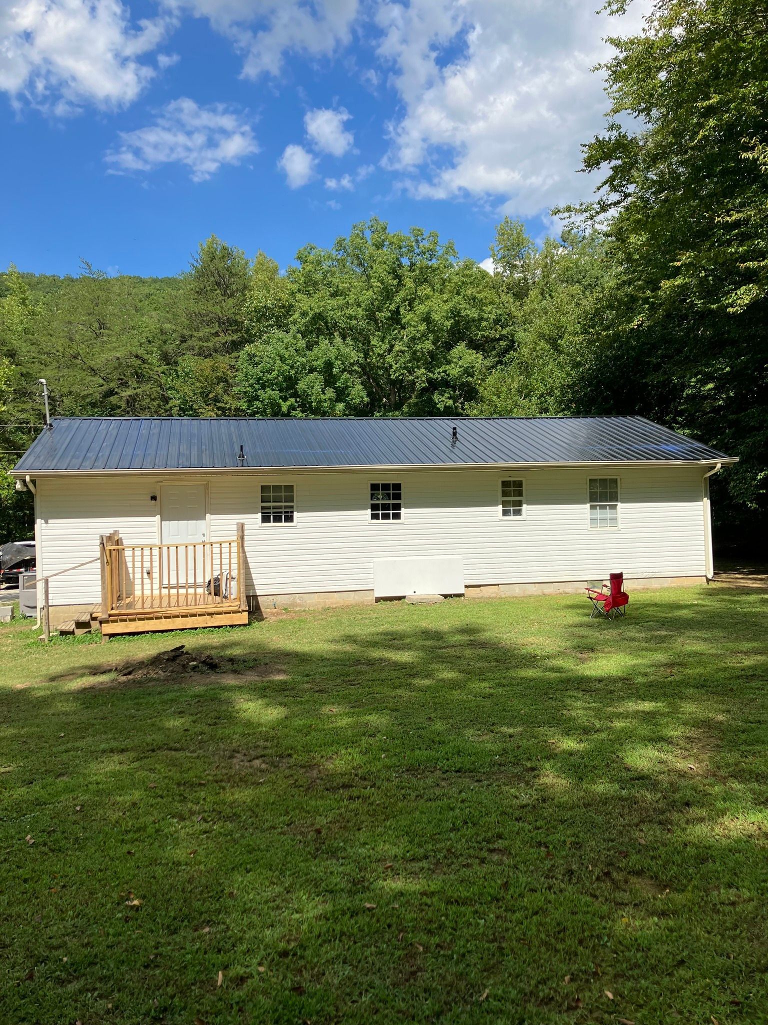 A white house with a black roof is sitting on top of a lush green field.