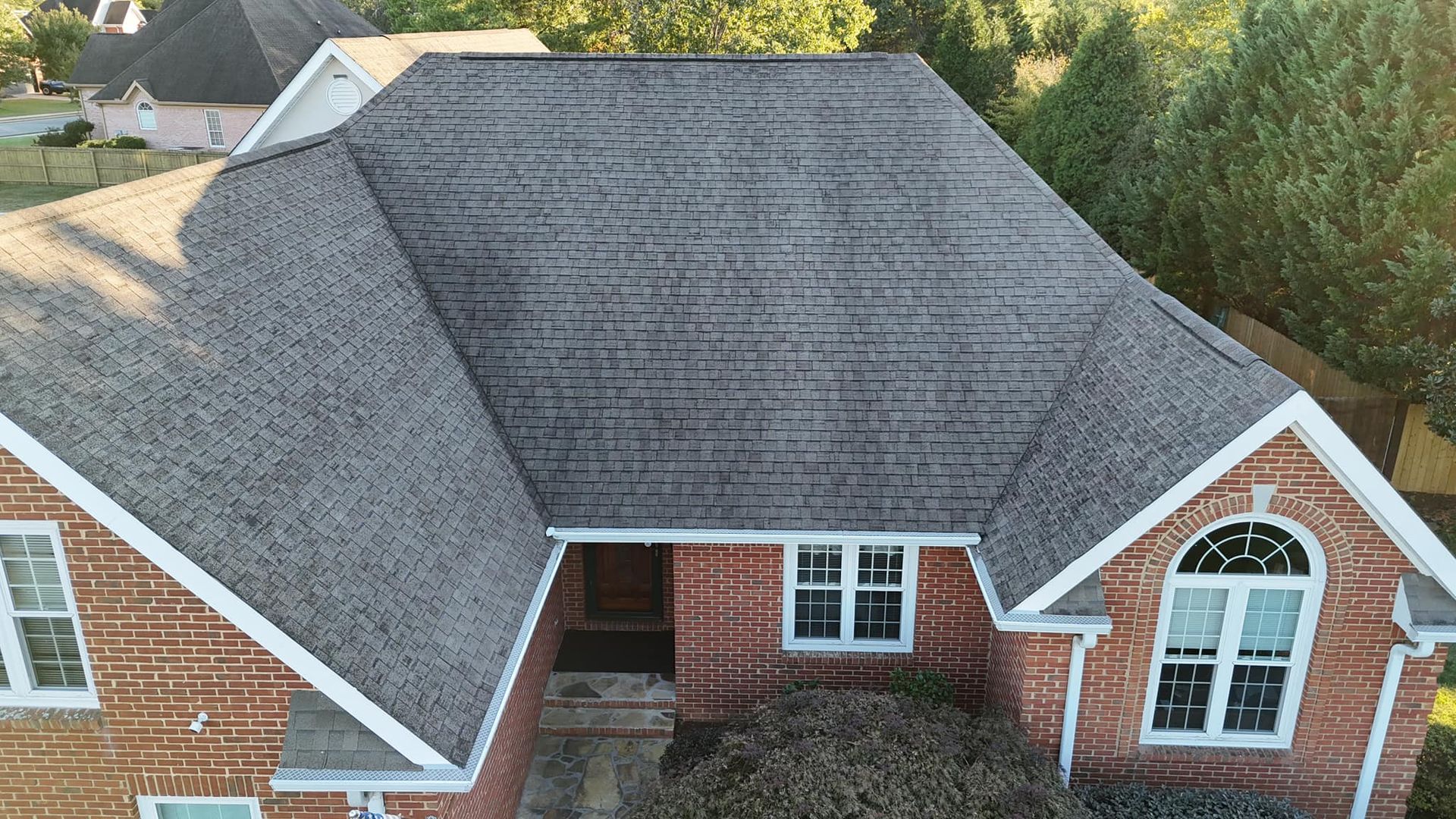 An aerial view of a large brick house with a gray roof.