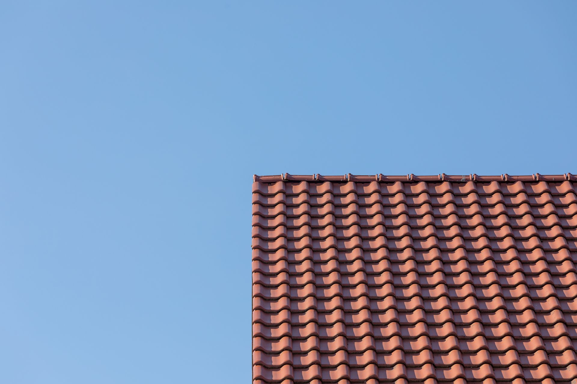 A red tiled roof with a blue sky in the background.