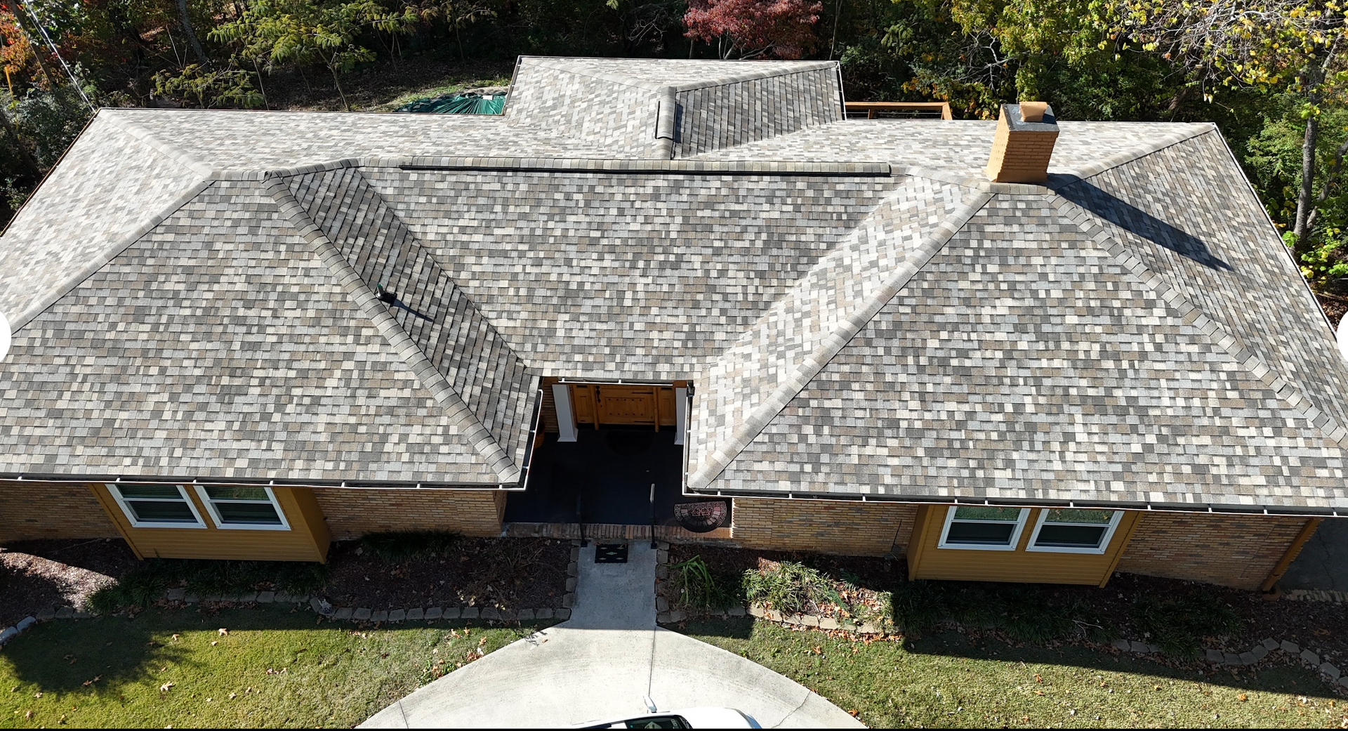 An aerial view of a house with a large roof and a car parked in front of it.