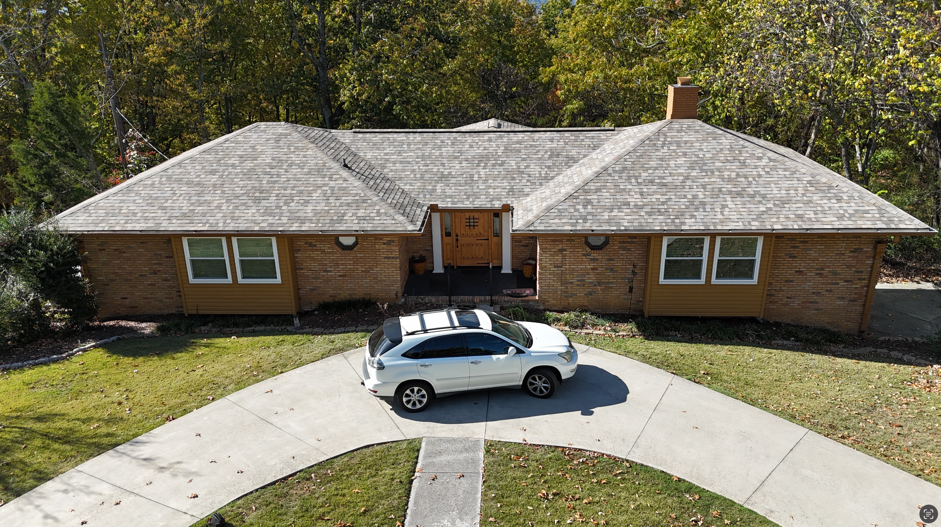 A white car is parked in front of a log cabin.